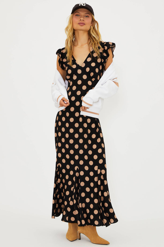 Woman wearing a black polka dot dress with a white jacket on a white background