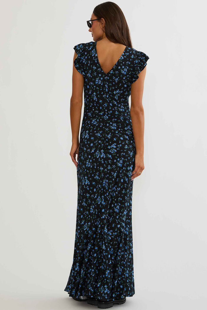 Woman wearing black maxi dress with blue florals on a white background.
