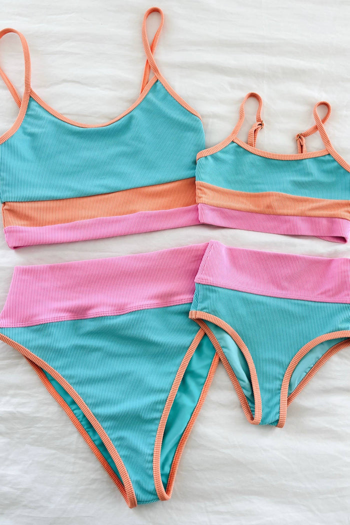 Colorful bikini set with turquoise, pink, and orange stripes on a white background