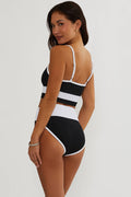 Woman wearing a black and white striped swimsuit on a plain background
