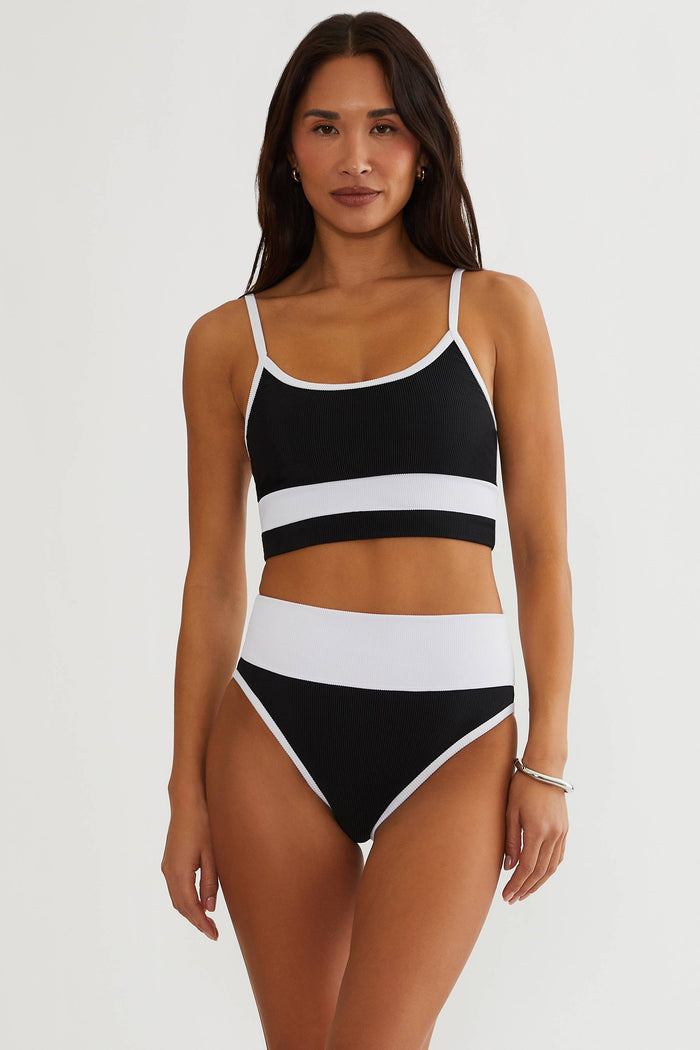 Woman wearing a black and white striped swimsuit on a plain background