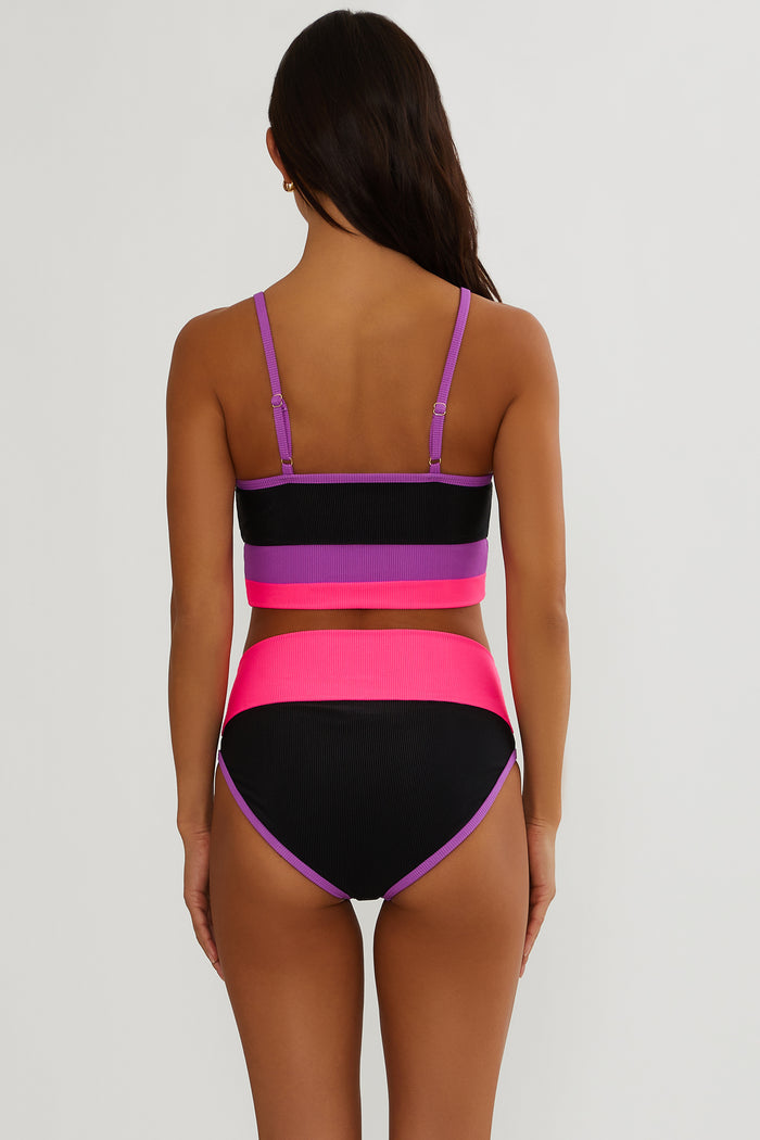Woman wearing a colorful bikini set with pink, purple, and black colors on a white background.