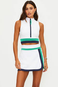 Woman wearing a white sleeveless top and skirt with green and navy accents on a white background