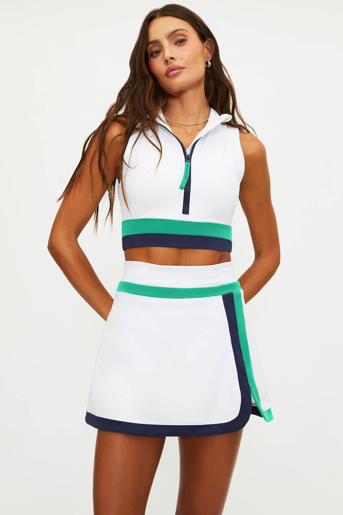 Woman wearing a white sleeveless dress with green and navy accents on a white background