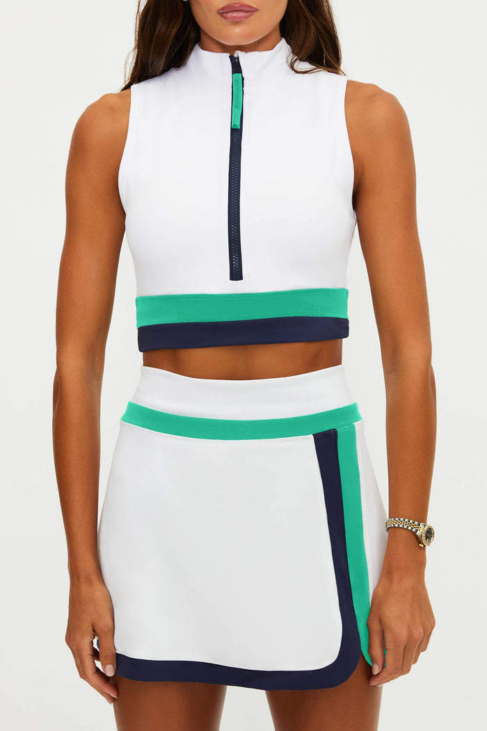 Woman wearing a white sleeveless top with green and navy accents on a white background