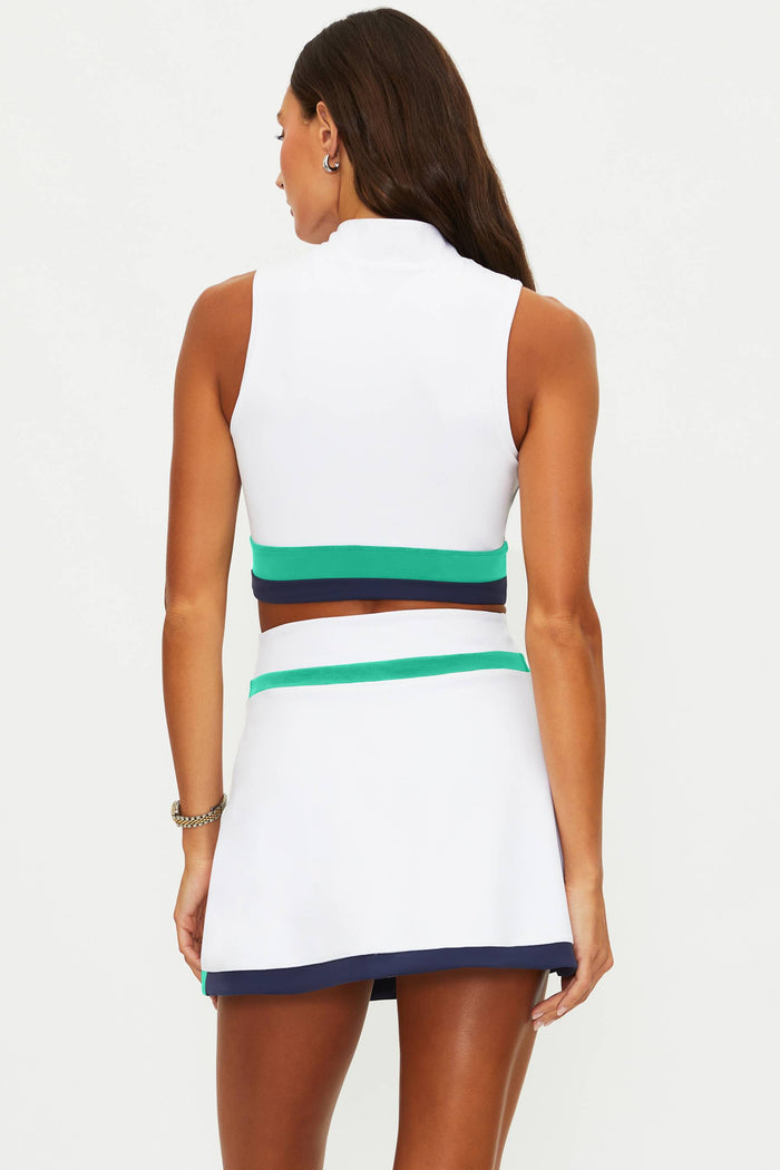 Woman wearing a white sleeveless top and skirt with green and navy accents on a white background