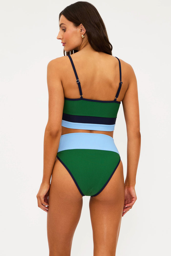 Woman wearing a colorful bikini set with green, blue, and black straps on a white background