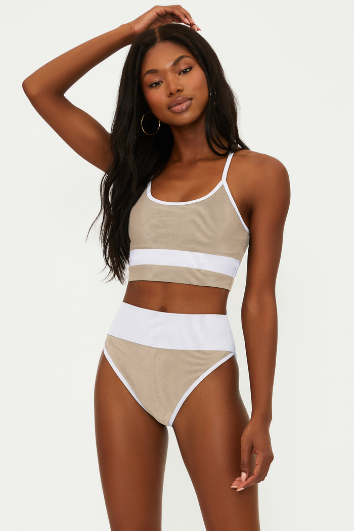 Woman wearing a beige and white bikini set on a plain background
