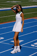 Woman in a white dress standing on a blue track with green grass in the background