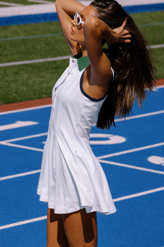 Woman in a white dress standing on a blue track and field surface