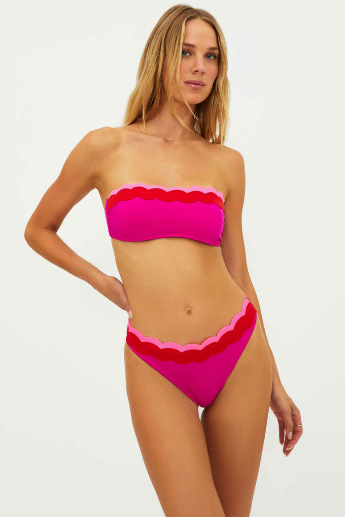 Woman wearing a pink bikini with scalloped edges on a white background