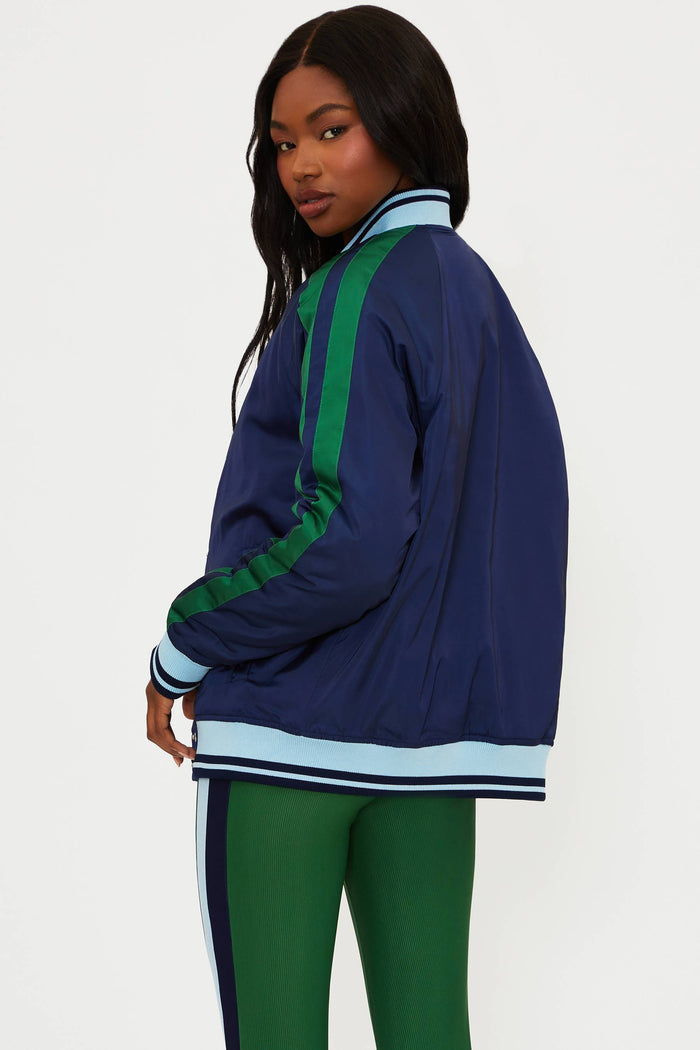 Woman wearing a blue tracksuit with green accents on a white background