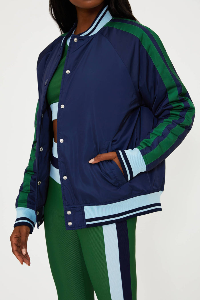 Person wearing a navy and green jacket with matching pants on a white background