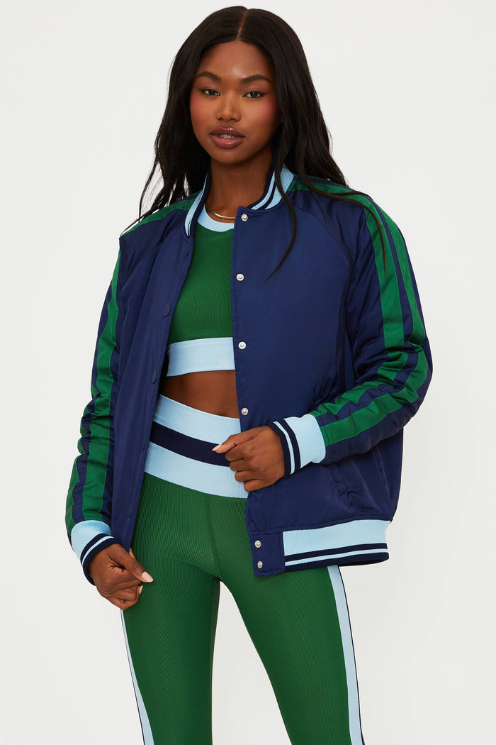 Woman wearing a blue and green jacket with matching pants on a white background