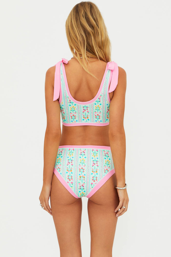 Woman wearing a floral two-piece swimsuit with pink straps on a white background