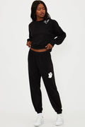 Person wearing a black tracksuit with ghost design on a white background