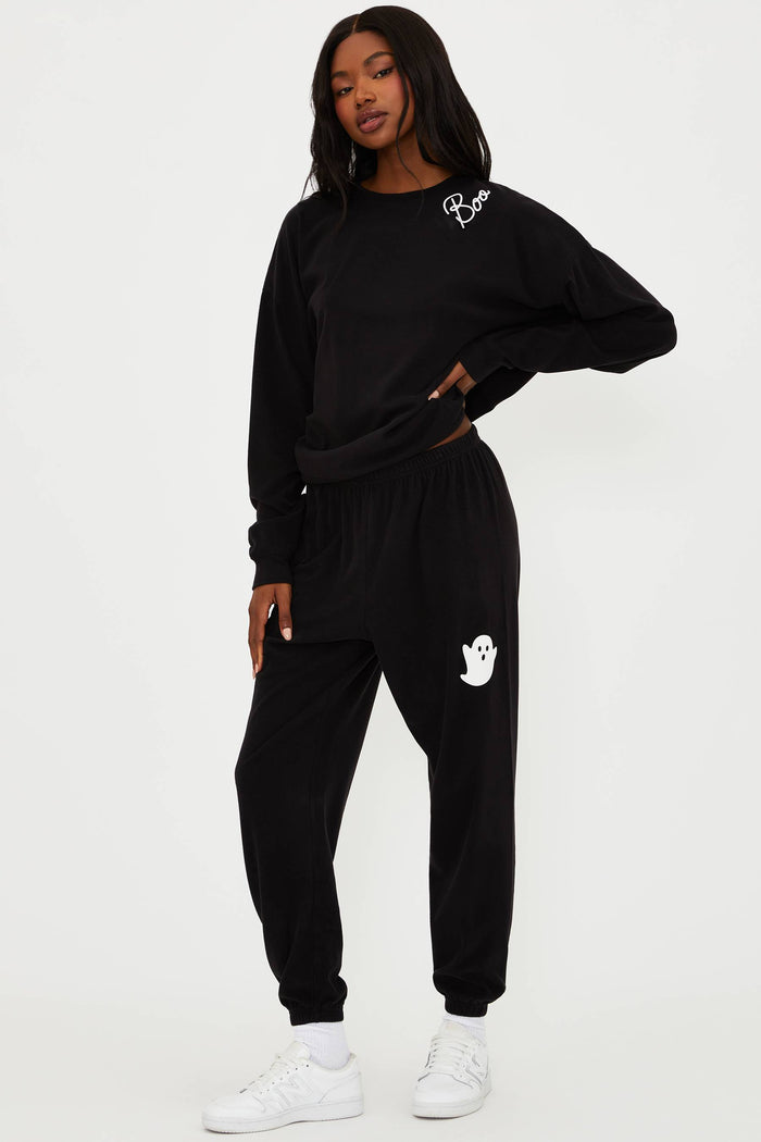 Person wearing a black tracksuit with white ghost designs on a white background