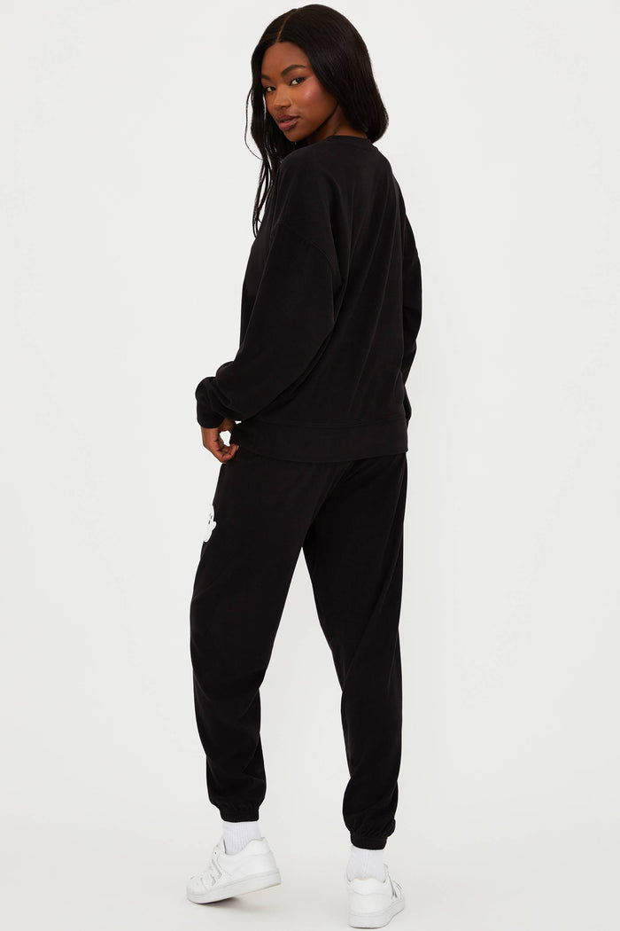 Person wearing a black tracksuit with white sneakers on a white background