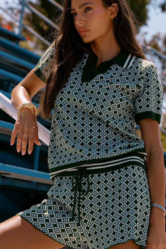 Woman wearing a patterned dress sitting outdoors.