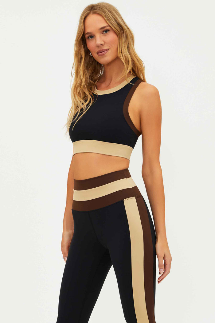 Woman wearing a black and beige athletic outfit on a white background