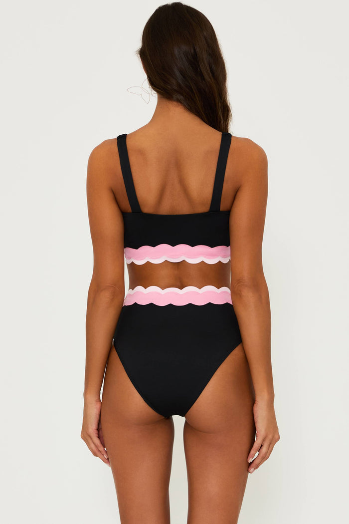 black bralette style swim top with pink contrast wavy trim and a black high waist bottom with pink wavy trim and the top of the waist band