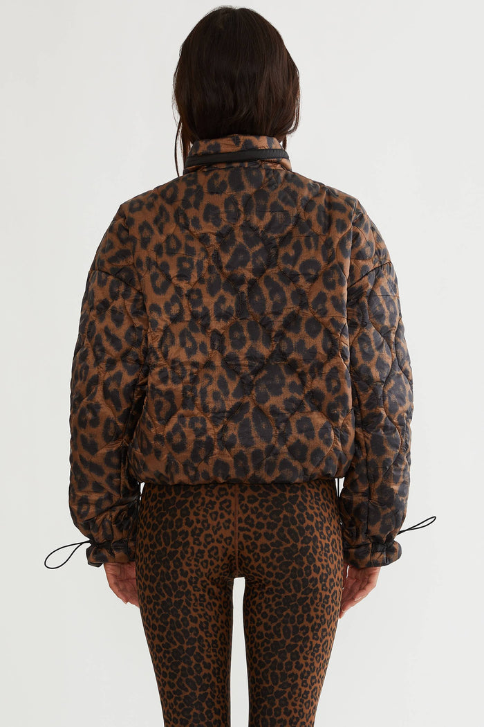 Woman wearing brown and black leopard puffer jacket.