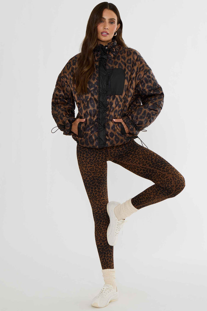 Woman wearing brown and black leopard puffer jacket.