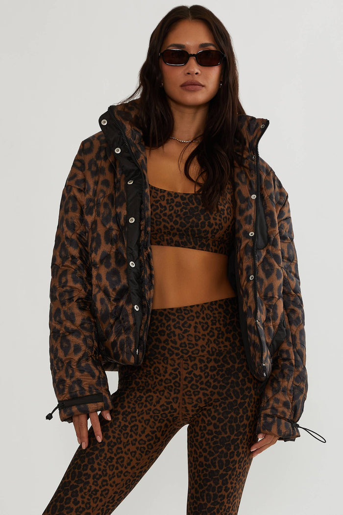 Woman wearing brown and black leopard puffer jacket.