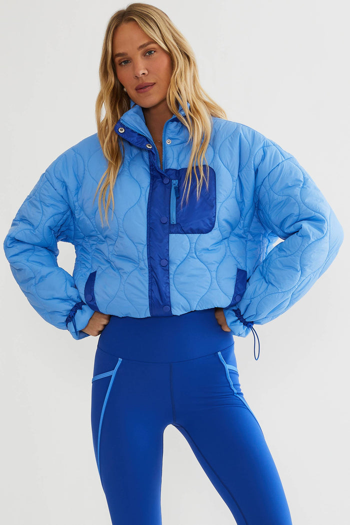Woman wearing baby blue puffer jacket with royal blue accents.