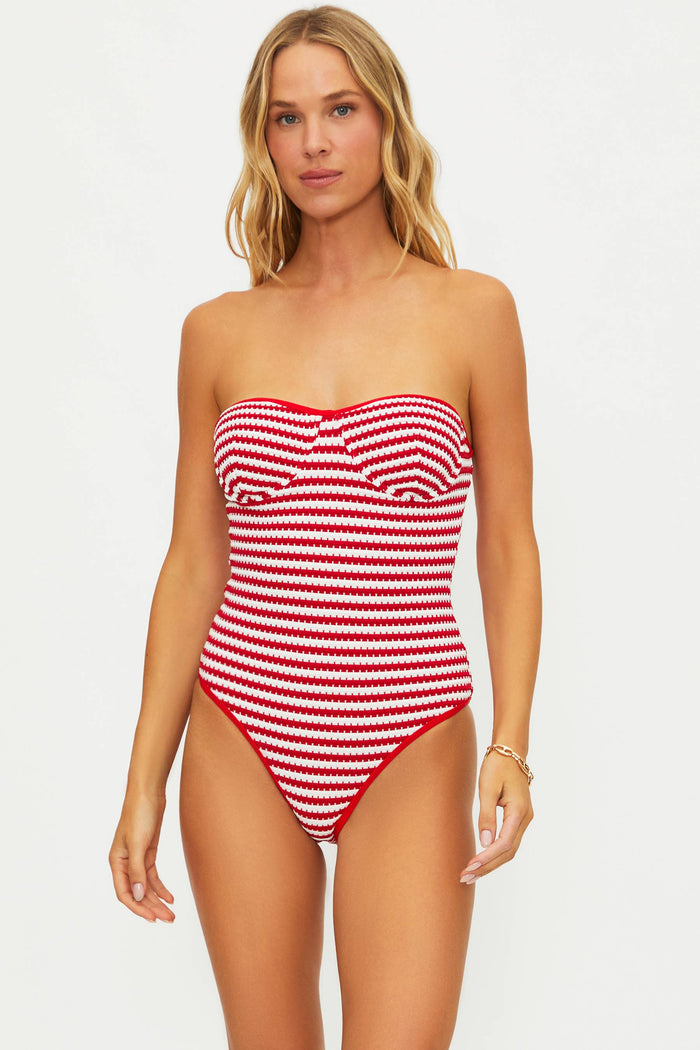 Woman wearing a red and white striped swimsuit on a plain background