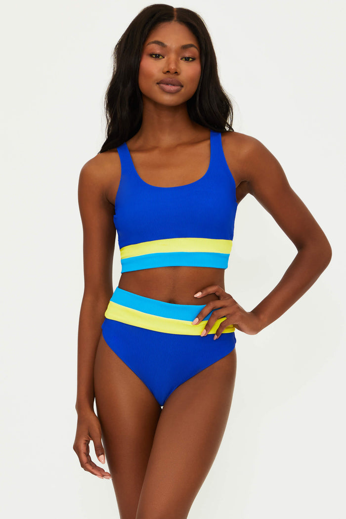A model is wearing a blue and yellow striped high waist swim bottom.