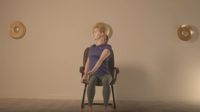 Instructor performing one of our hernia rehabilitation exercises, seated in a chair.