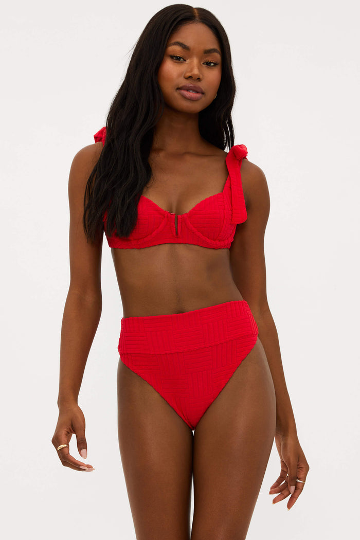 This image features the "Highway Bottom Cherry Terry," a stylish and vibrant high-waisted swim bottom. The model is showcased wearing the cherry red, terry fabric swim bottoms, which offer moderate coverage with a cheeky cut.
