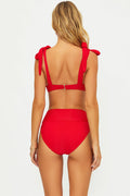 Red bikini with bow straps worn by a model on a white background