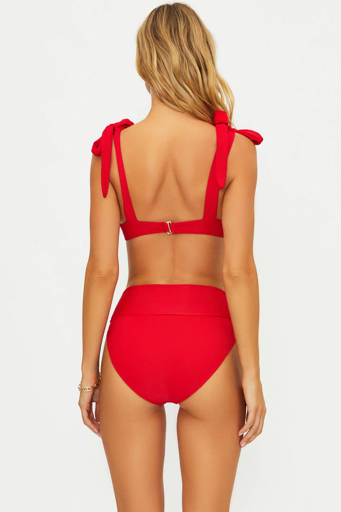 Red bikini with bow straps worn by a model on a white background