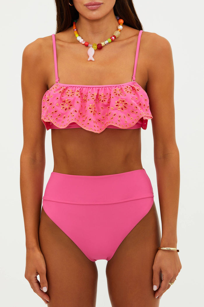 Woman wearing a pink bikini with floral top and high-waisted bottom on a white background
