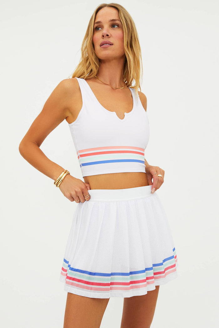 Woman wearing a white crop top with colorful stripes and a matching skirt on a white background