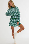 Woman wearing a green and white checkered outfit with a matching belt on a white background