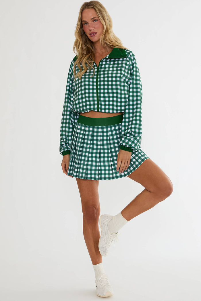 Woman wearing a green and white checkered outfit with a skirt and top on a white background