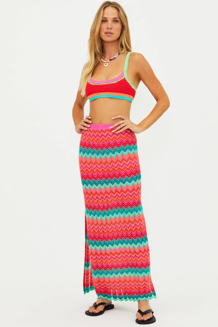 Woman wearing a colorful striped top and skirt on a white background