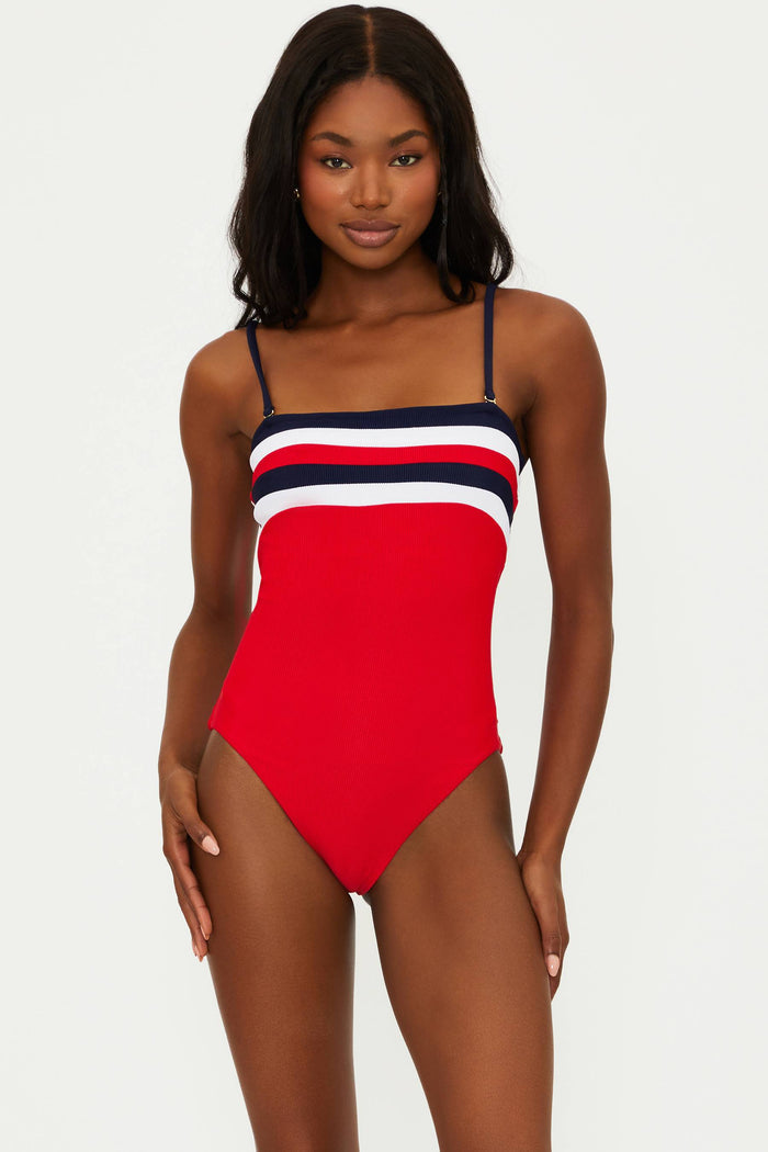 A model wearing a red, white, and blue one-piece swimsuit with a colorblock design.