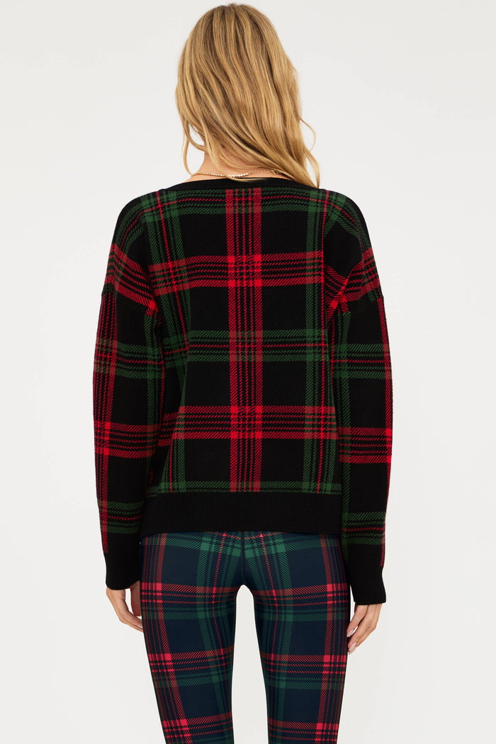 Person wearing a plaid sweater and pants on a white background