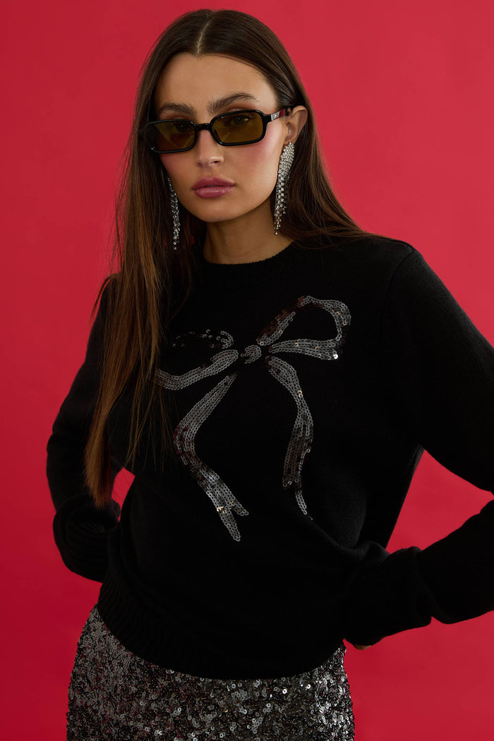 Woman wearing a black sweater with a spider design against a red background