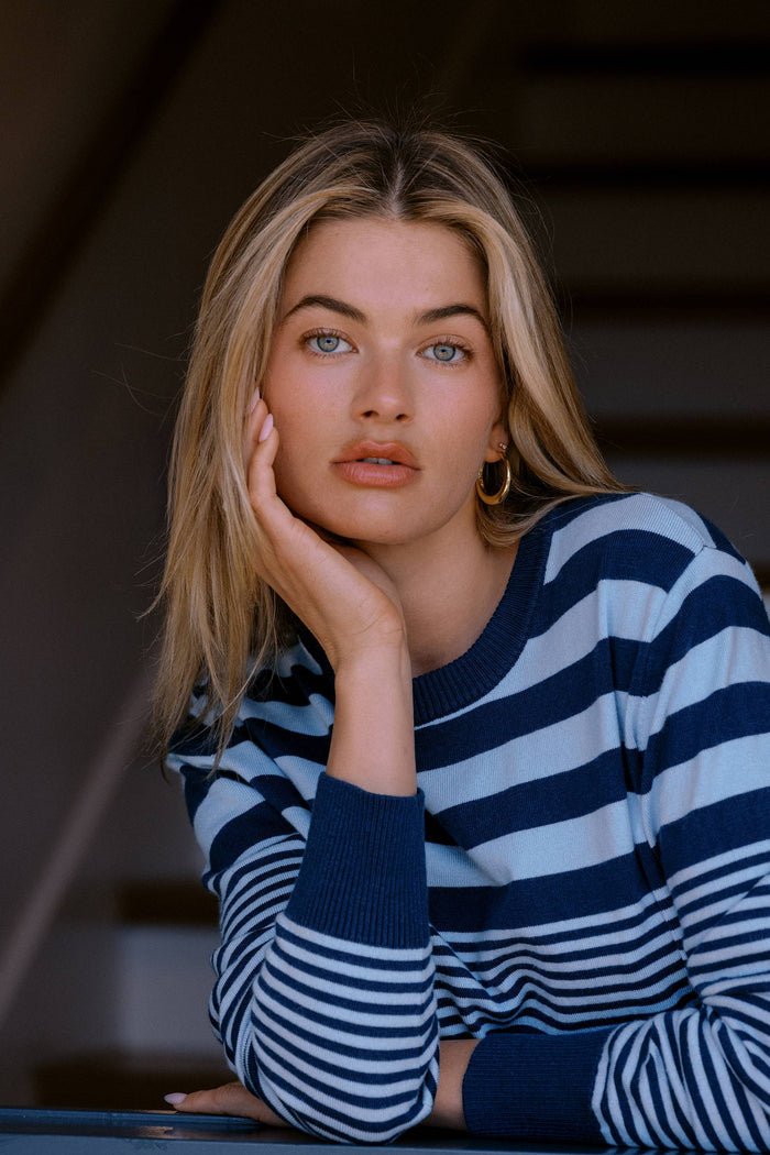 Woman wearing a blue and white striped sweater with a blurred background
