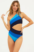 A model wearing a blue and black color-blocked asymmetrical one-piece swimsuit with a side cutout.