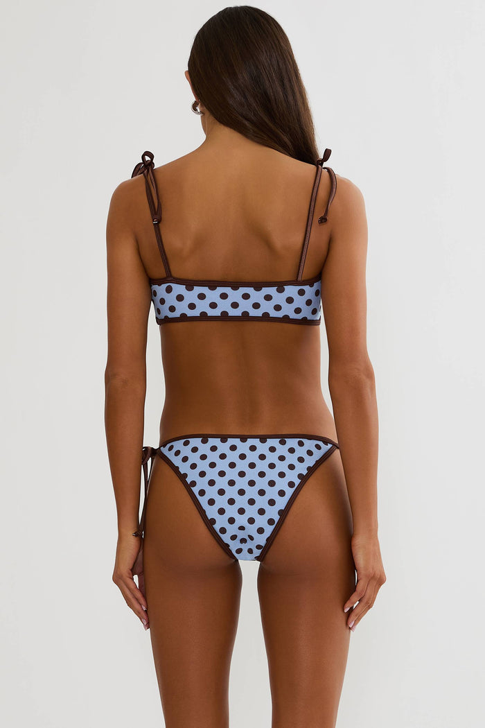 Woman wearing a brown and blue polka dot bikini on a white background