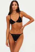 Woman wearing a black bikini with cherry pattern on a white background