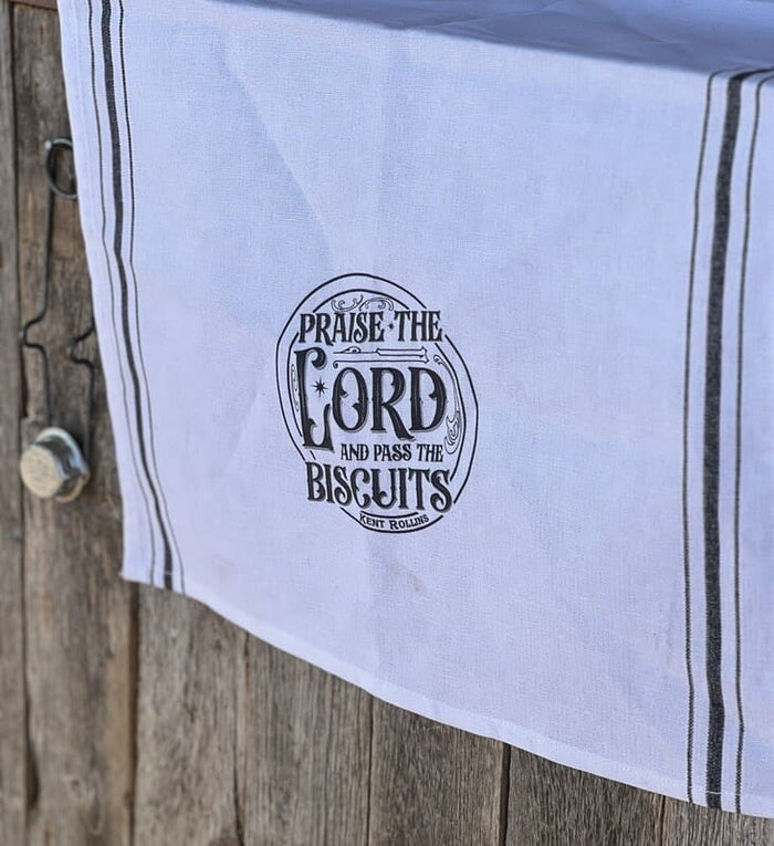White tea towel with "Praise the Lord and pass the biscuits"
