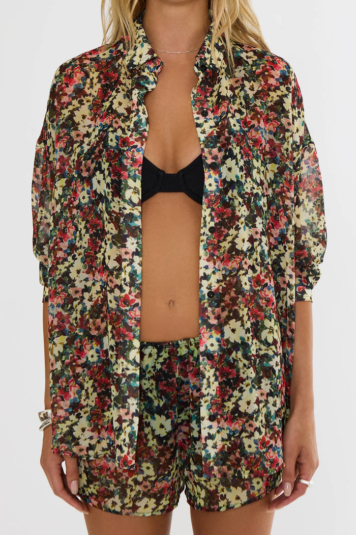 Person wearing a colorful floral shirt and shorts set on a white background