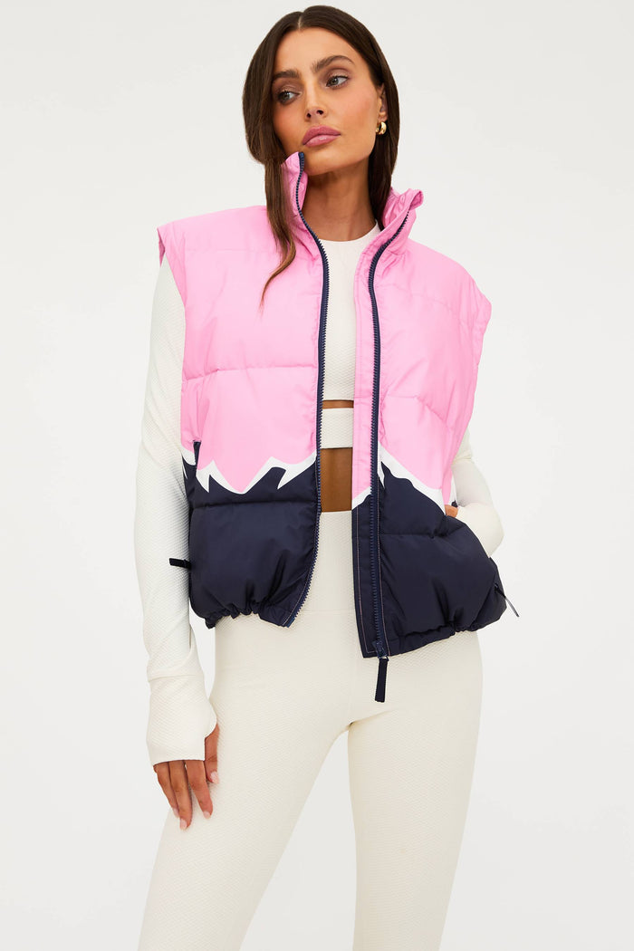 Woman wearing a pink and navy puffer vest on a white background